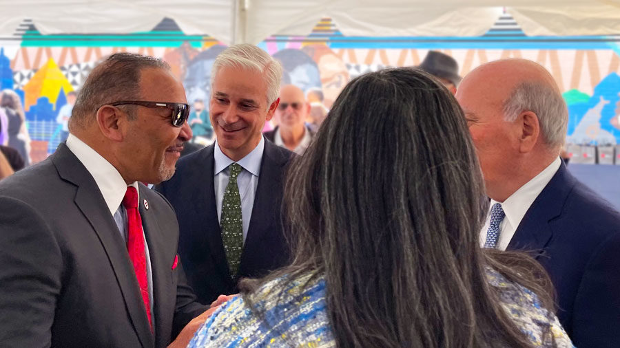 Marc Morial and Charlie Scharf stand in a crowd talking to people.