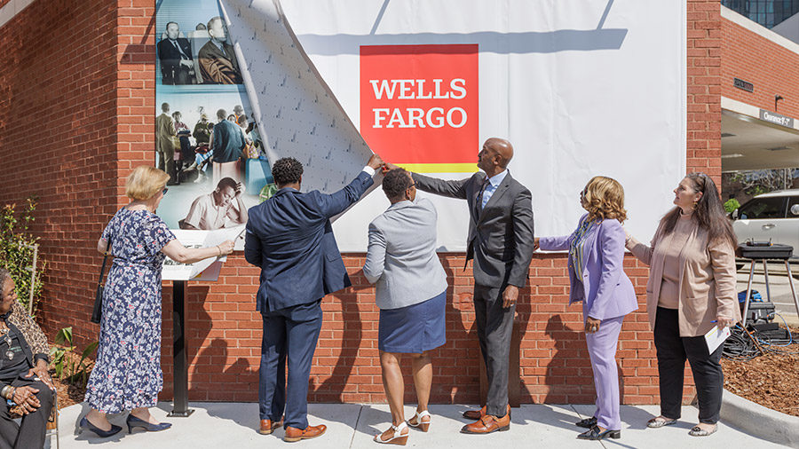 Six individuals work together to unveil the Freedom Riders mural.