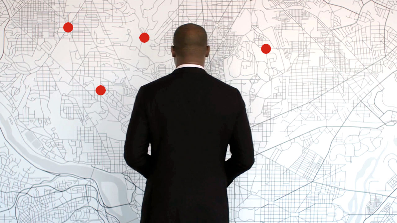 A man looks over a wall-mounted map of a city.