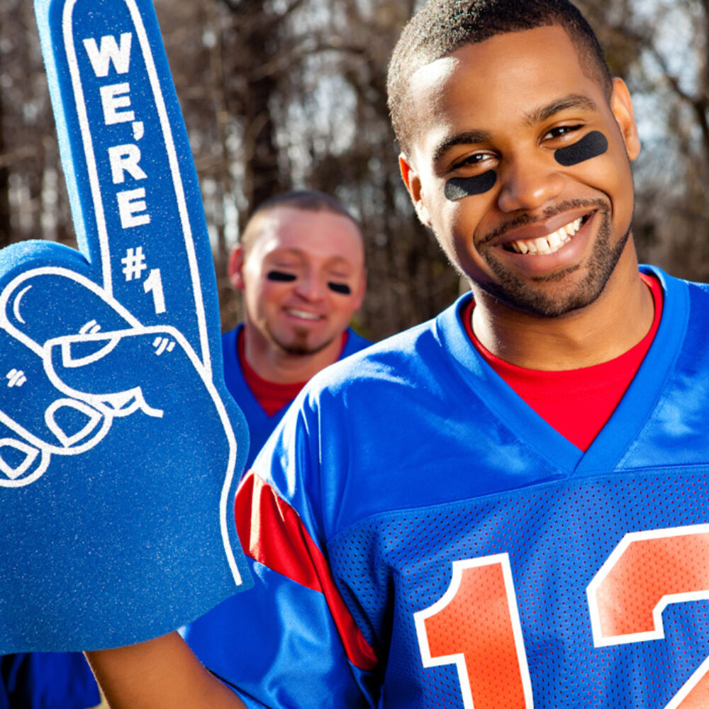 A man in a blue sports jersey has a We’re #1 foam finger.