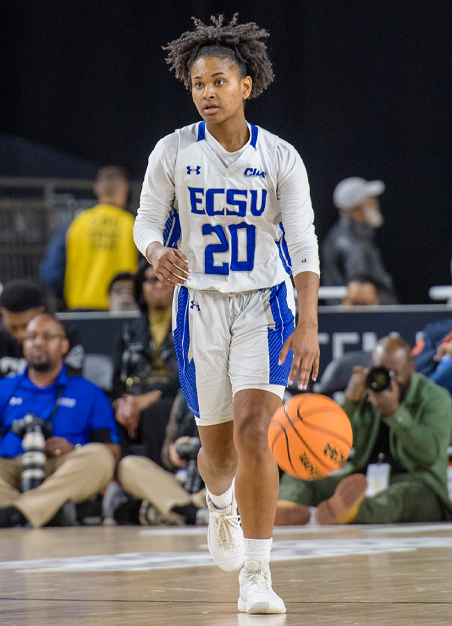 A college basketball players dribbles the ball with her left hand.