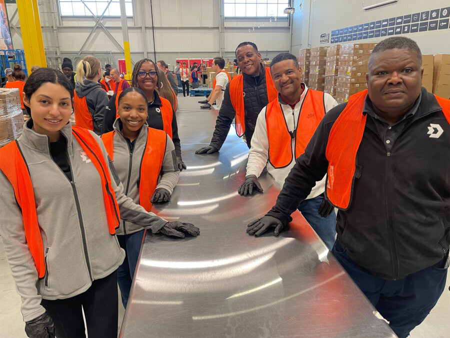 A group of people wearing orange work vests volunteer at Forgotten Harvest in Detroit.