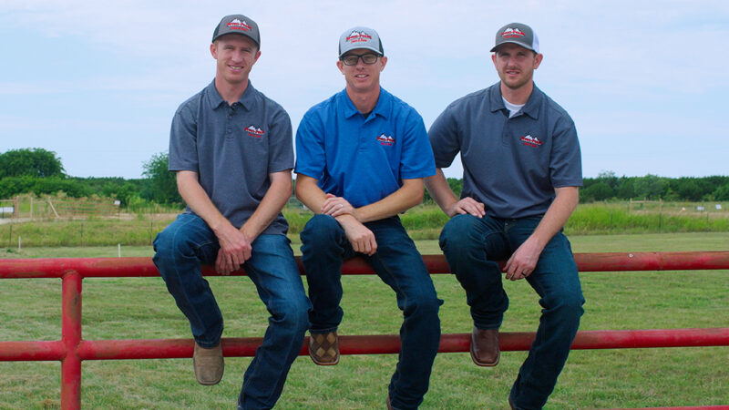 Seven Peaks Fence and Barn owners Trevor, Jeff, and Matt Chandler sit on livestock fence at a family home.