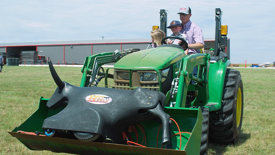 Jeff Chandler and two young children drive a tractor transporting a dummy rodeo calf.