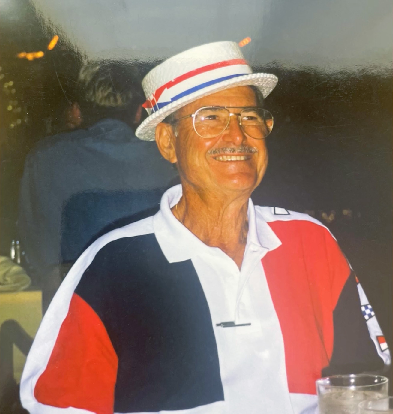 An image of a man in a red, white, and blue shirt and matching boater hat.