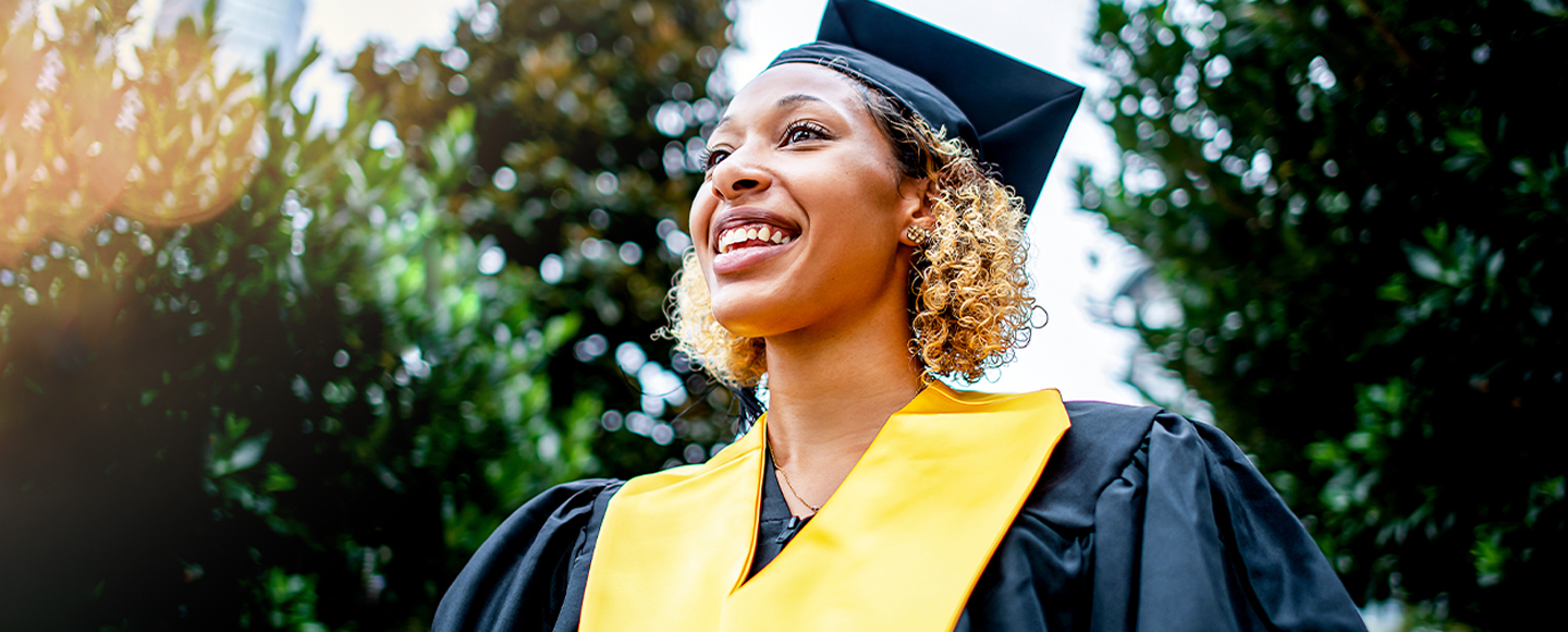 A smiling woman in a graduation cap and gown