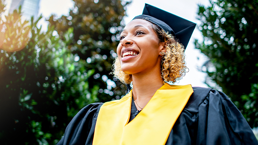 A smiling woman in a graduation cap and gown