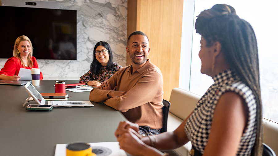 4 people are sitting at a conference table with smiles on their faces