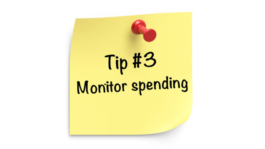 “Tip #3 Monitor spending.” is typed on a yellow sticky note with a red pin on white background.